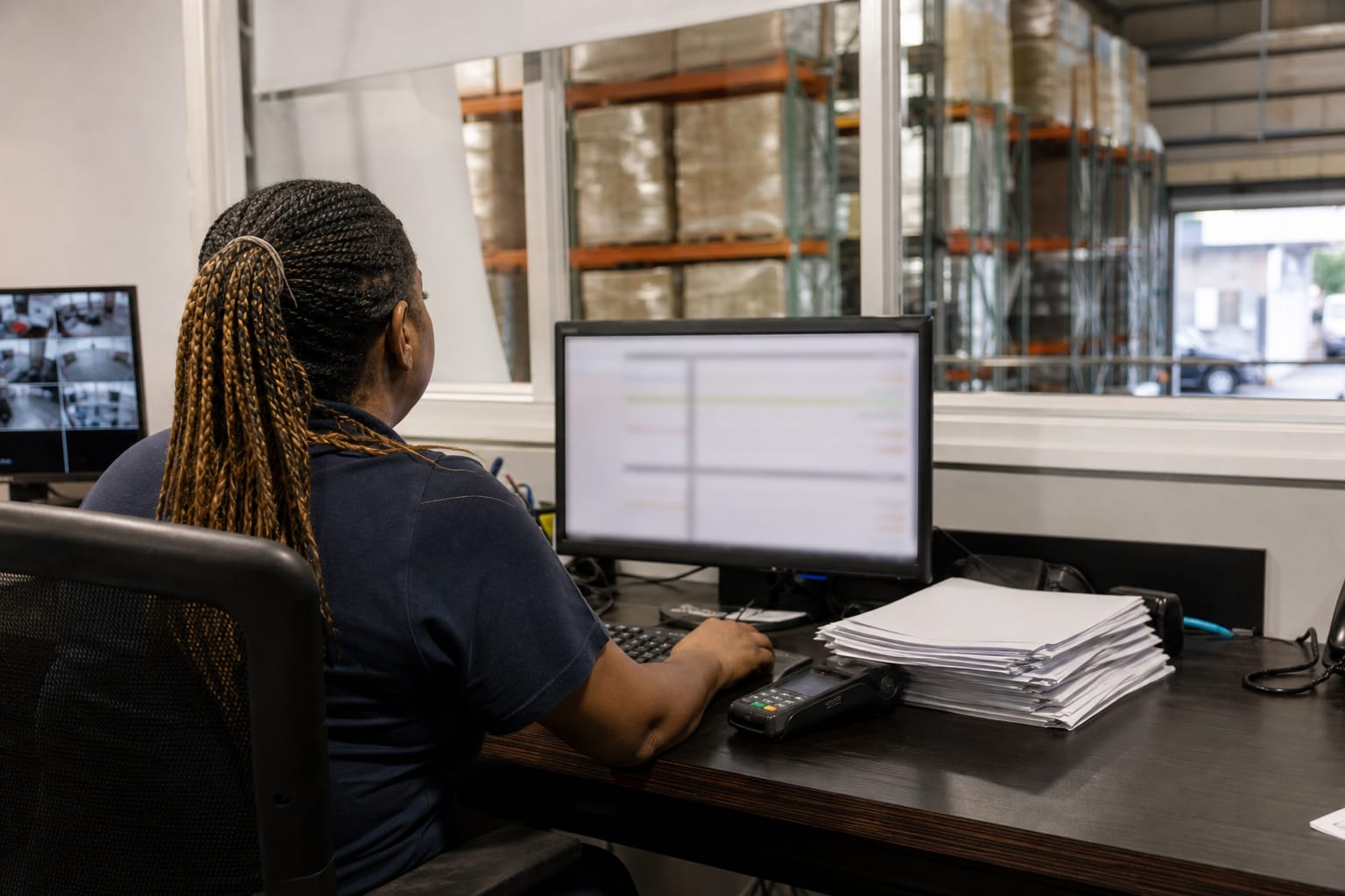 Billing clerk reviewing moving invoices on screen with a card reader and signed paperwork nearby.
