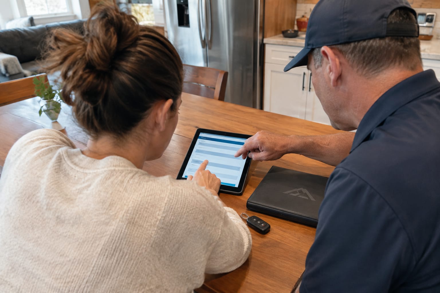 Homeowner signing a moving quote on a tablet while an estimator points to a line item